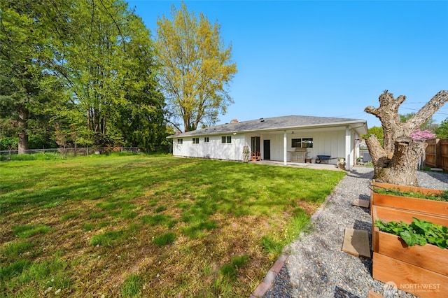 rear view of house with a garden, a patio area, a fenced backyard, a lawn, and board and batten siding