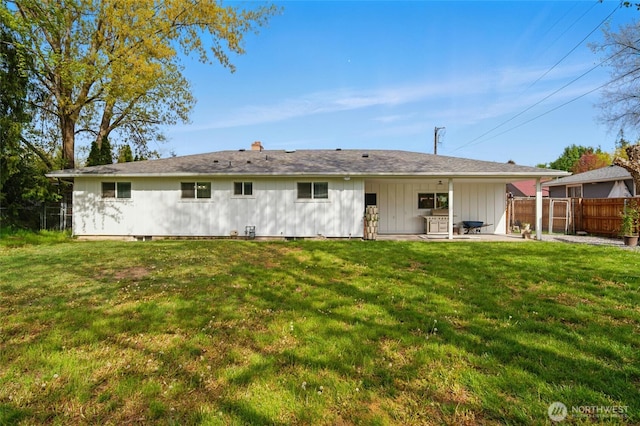 back of property featuring a patio, fence, a chimney, and a yard