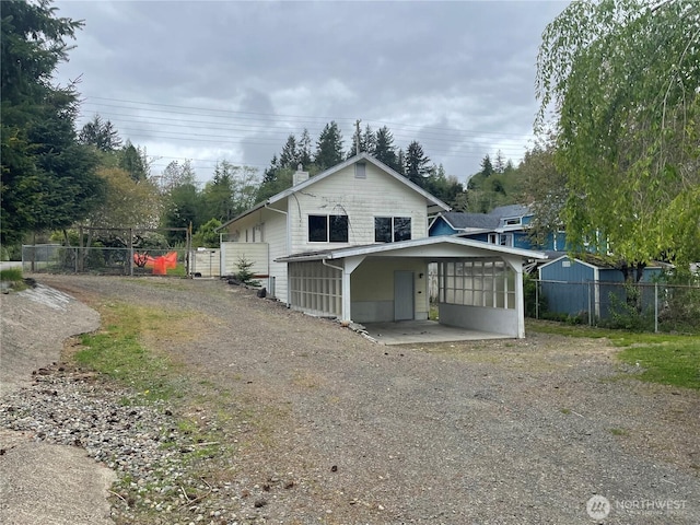 rear view of property with fence, a chimney, a sunroom, and dirt driveway