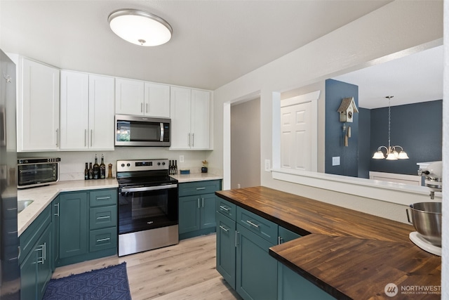 kitchen featuring stainless steel appliances, wooden counters, white cabinets, light wood finished floors, and a chandelier