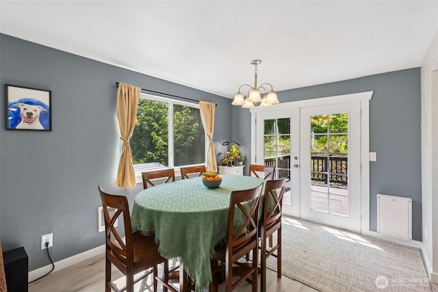 dining space with a chandelier, light wood finished floors, french doors, and baseboards