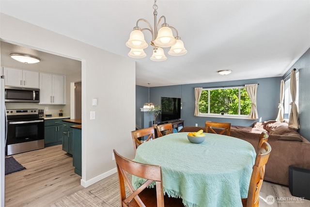 dining space featuring a chandelier, light wood finished floors, and baseboards