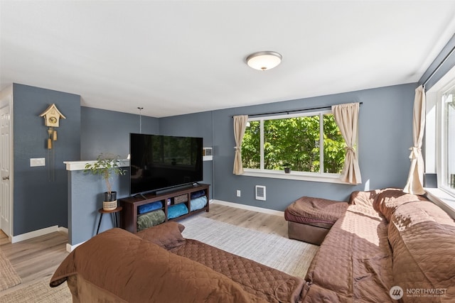 living room featuring healthy amount of natural light, wood finished floors, and baseboards