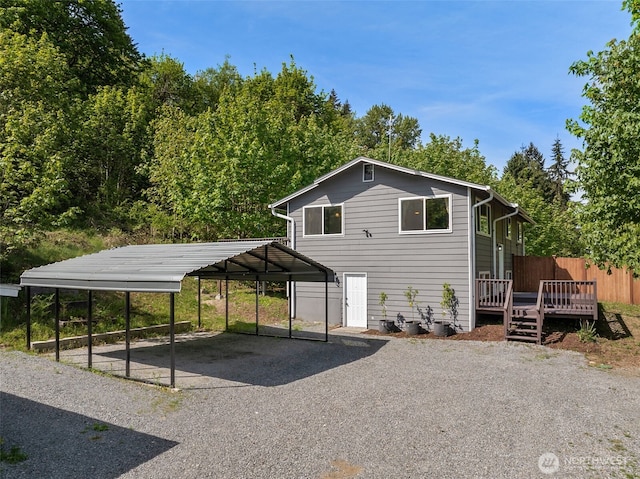 view of front of home featuring a deck, gravel driveway, and a carport