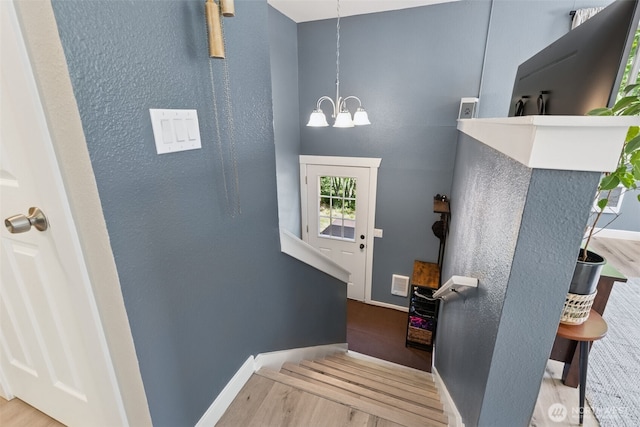 entryway with wood finished floors, a chandelier, and baseboards