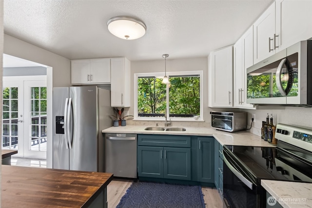 kitchen with stainless steel appliances, white cabinetry, light wood-style floors, a sink, and a textured ceiling
