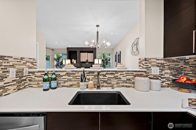 kitchen featuring stainless steel dishwasher, a sink, light countertops, and tasteful backsplash