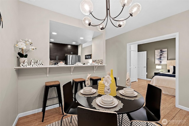 dining room featuring an inviting chandelier, baseboards, recessed lighting, and light wood-style flooring