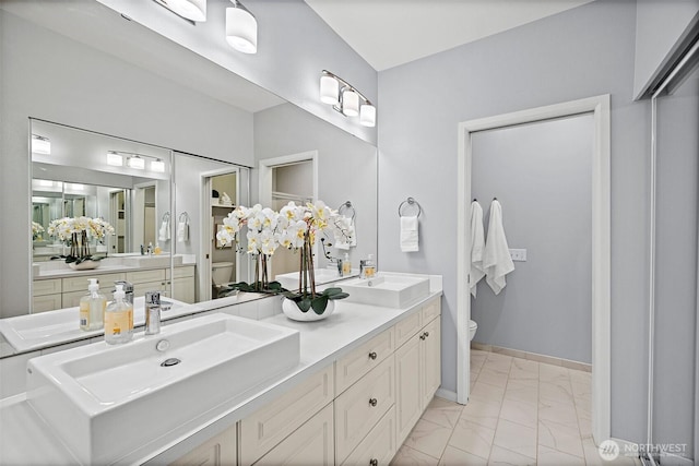 bathroom featuring a sink, toilet, double vanity, and marble finish floor