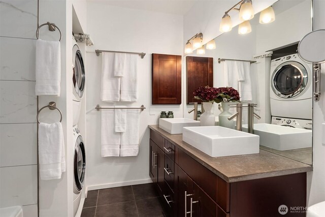 full bath featuring double vanity, tile patterned floors, a sink, and stacked washer / dryer