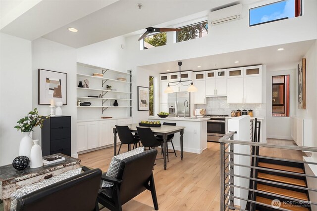 interior space featuring a high ceiling, light wood finished floors, and a wall unit AC