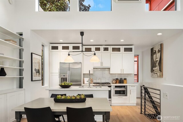 kitchen with white cabinets, appliances with stainless steel finishes, light countertops, plenty of natural light, and backsplash