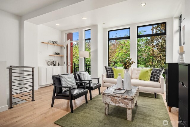 living area with light wood-style floors, recessed lighting, plenty of natural light, and an upstairs landing