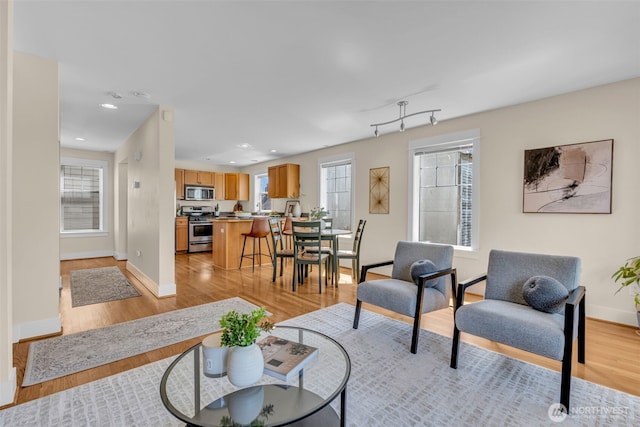 living room with recessed lighting, baseboards, and light wood-style flooring