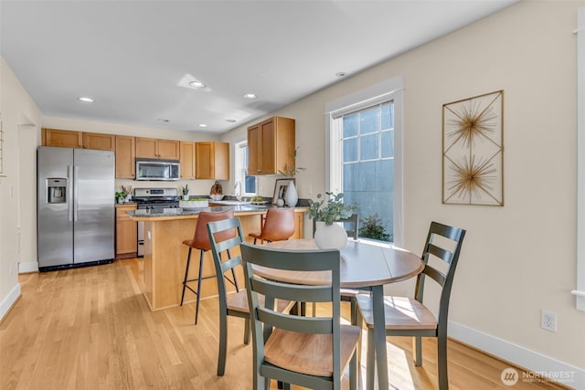 dining room featuring baseboards, recessed lighting, and light wood-style flooring