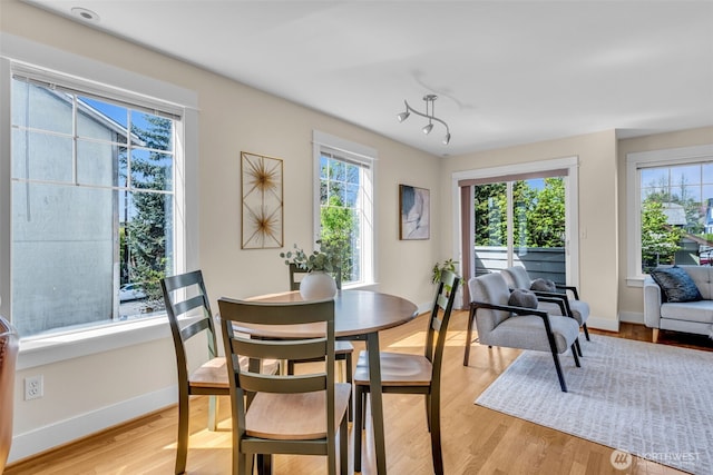 dining space featuring baseboards, light wood finished floors, and a healthy amount of sunlight