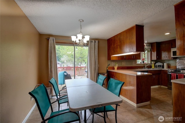 dining area featuring light tile patterned floors, plenty of natural light, a textured ceiling, and a notable chandelier