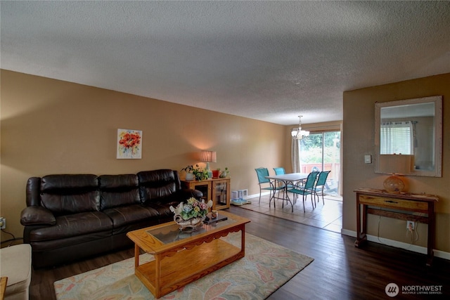 living room with an inviting chandelier, a textured ceiling, baseboards, wood finished floors, and visible vents
