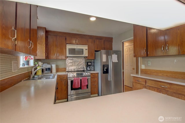kitchen with light countertops, appliances with stainless steel finishes, decorative backsplash, and a sink