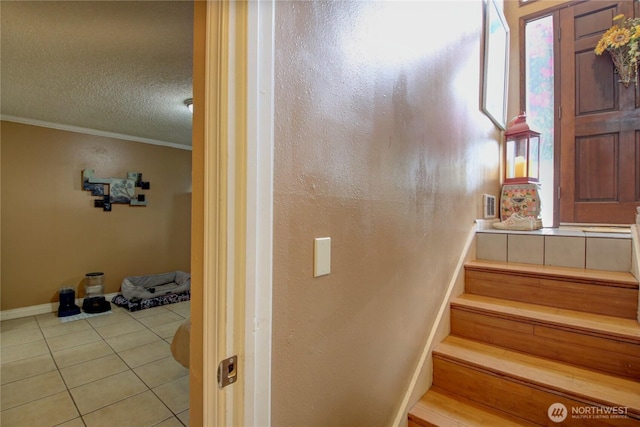stairway with baseboards, ornamental molding, a textured ceiling, and tile patterned floors