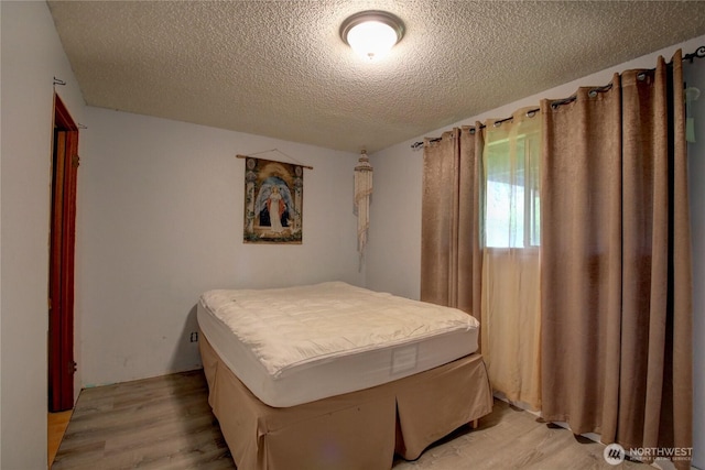 bedroom featuring light wood-style flooring and a textured ceiling