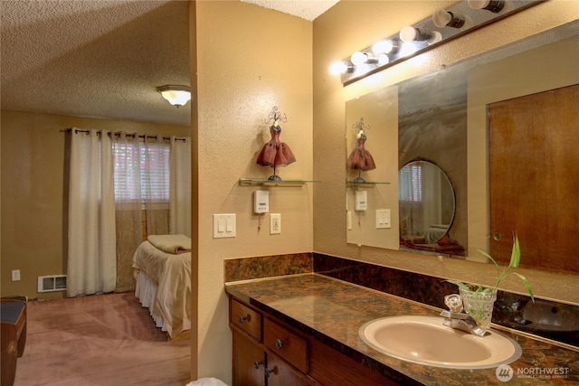 bathroom with vanity, a textured wall, a textured ceiling, and visible vents