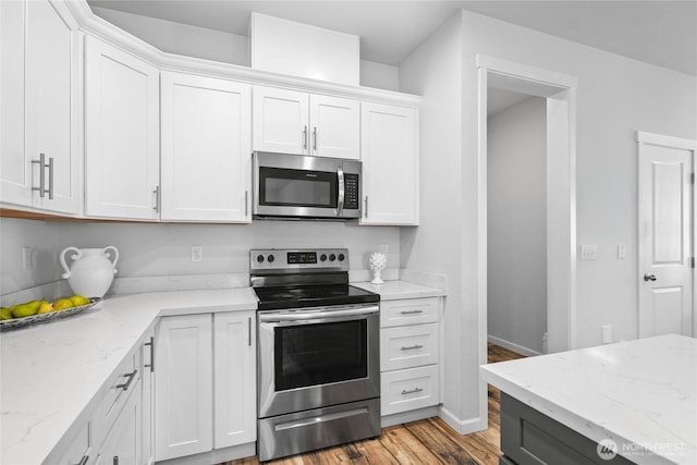1824 E Fairbanks St, Tacoma, WA 98404 - kitchen featuring appliances with stainless steel finishes, white cabinets, light wood-style flooring, light stone countertops, and baseboards