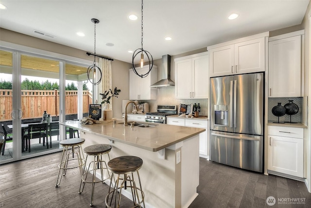 kitchen featuring a sink, stainless steel appliances, wall chimney exhaust hood, visible vents, and dark wood finished floors
