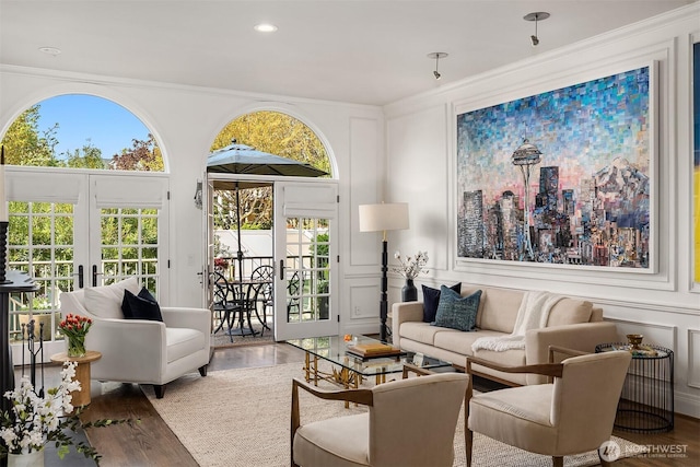 living room featuring a decorative wall, french doors, recessed lighting, wood finished floors, and ornamental molding