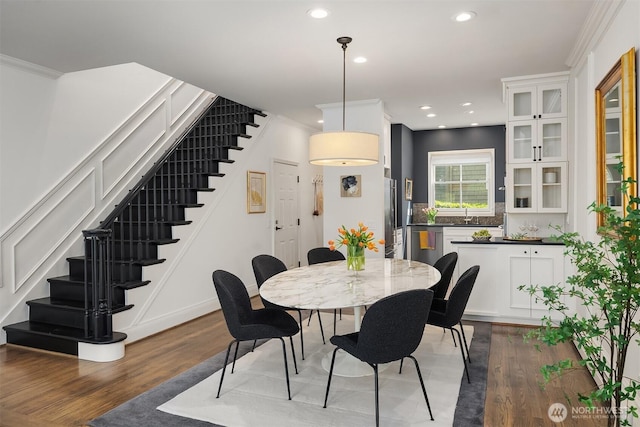 dining space featuring crown molding, recessed lighting, stairs, and wood finished floors
