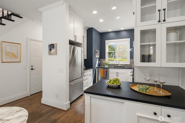 kitchen with dark countertops, white cabinets, a sink, dark wood finished floors, and stainless steel appliances