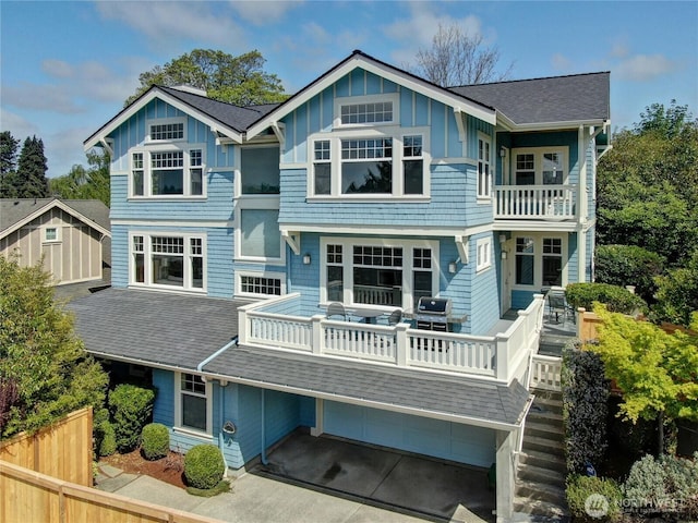7854 Stroud Ave N, Seattle, WA 98103 - rear view of property featuring a balcony, board and batten siding, driveway, a garage, and roof with shingles