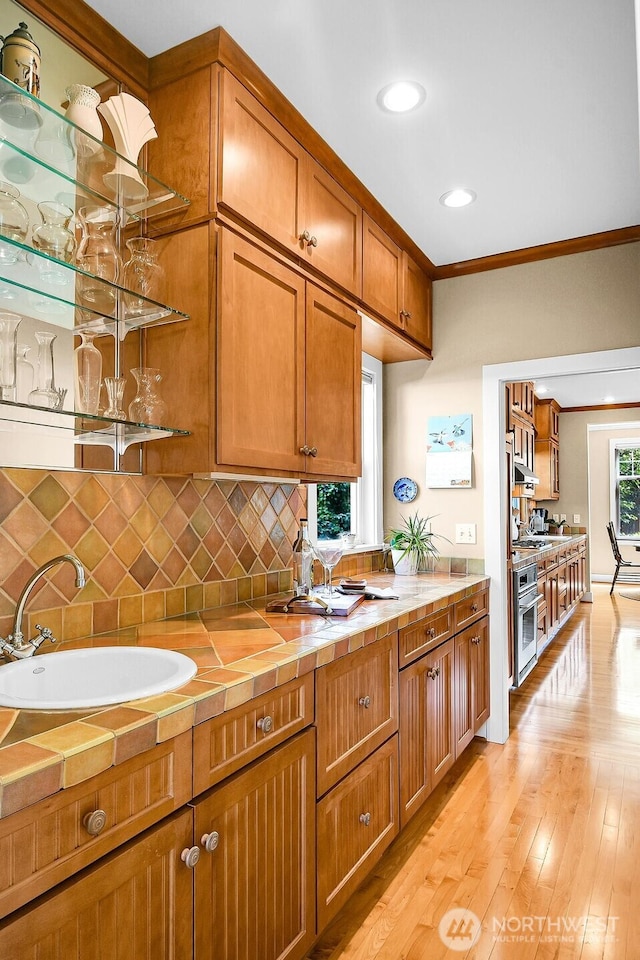 7854 Stroud Ave N, Seattle, WA 98103 - kitchen with brown cabinetry, a sink, decorative backsplash, tile counters, and oven