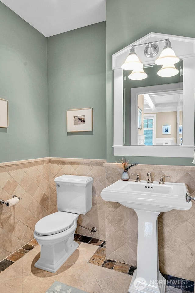 7854 Stroud Ave N, Seattle, WA 98103 - half bathroom featuring toilet, a sink, a wainscoted wall, tile patterned floors, and tile walls