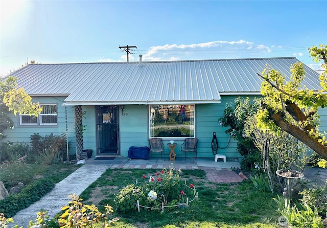 view of front of home with a patio, a front yard, and metal roof
