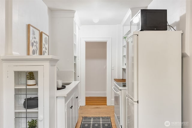 kitchen with white appliances, baseboards, light countertops, white cabinetry, and light wood-style flooring