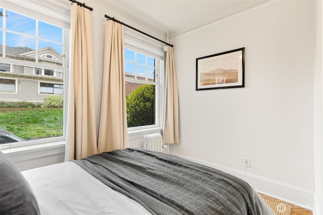 bedroom with baseboards, ornamental molding, and radiator