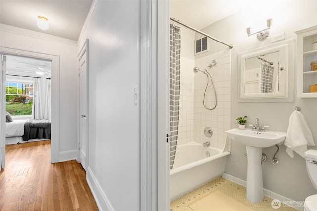bathroom with visible vents, wood finished floors, baseboards, toilet, and shower / tub combo with curtain