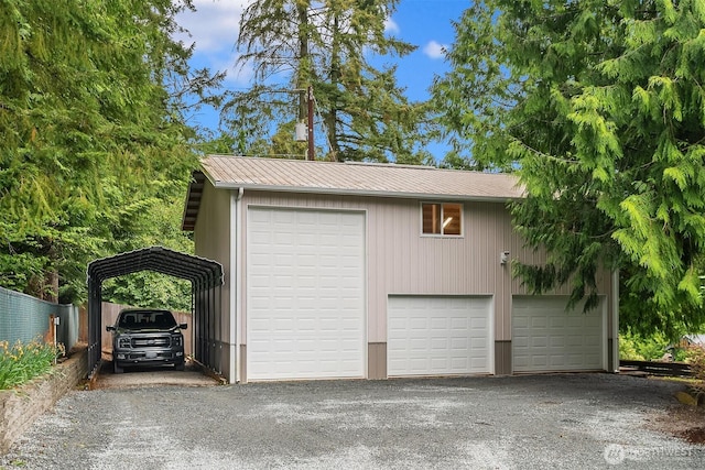 detached garage featuring fence and a carport