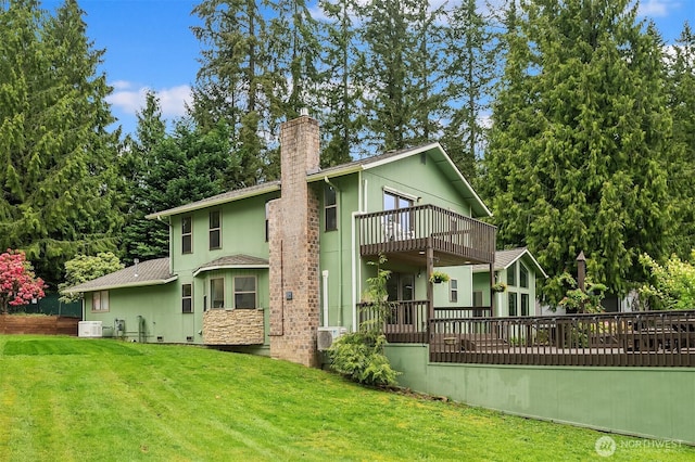 rear view of house with a lawn, a balcony, and a chimney