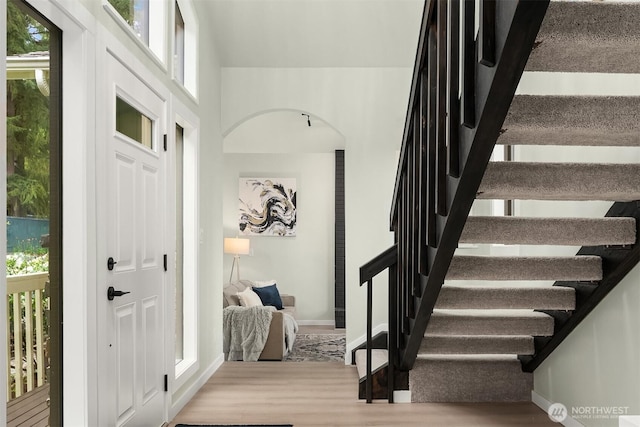 entrance foyer featuring baseboards, wood finished floors, and stairway