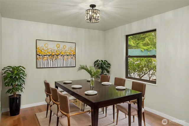 dining space with an inviting chandelier, baseboards, and wood finished floors