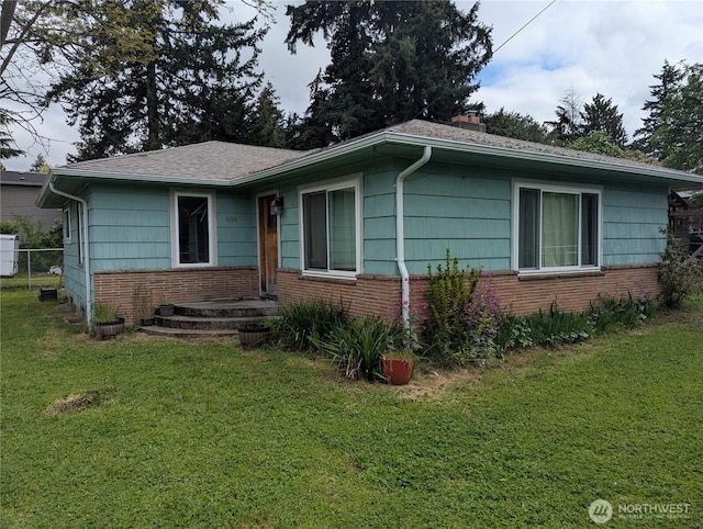 single story home with a front lawn, fence, roof with shingles, a chimney, and brick siding