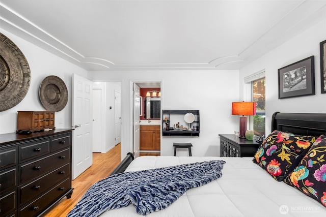 bedroom featuring ensuite bath and light wood-style flooring