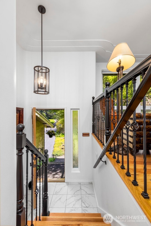 entrance foyer featuring stairs, baseboards, a wealth of natural light, and marble finish floor