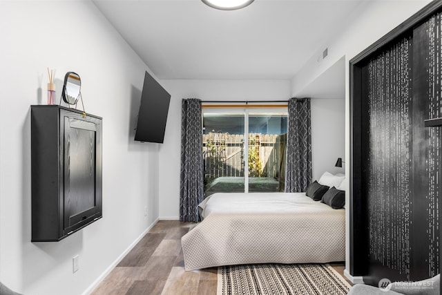 bedroom with baseboards, visible vents, and wood finished floors