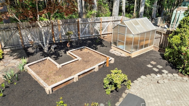 view of yard featuring an outbuilding, a garden, a fenced backyard, and a greenhouse