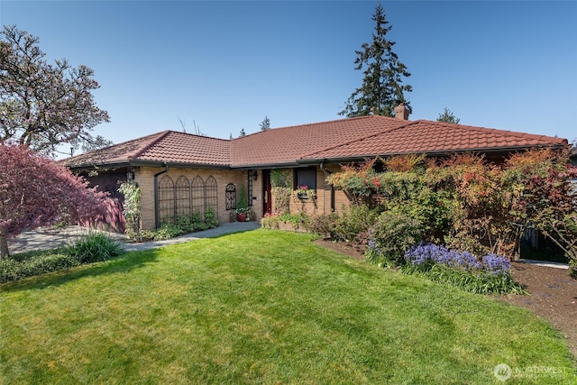 ranch-style home featuring a tiled roof, a garage, a chimney, and a front lawn