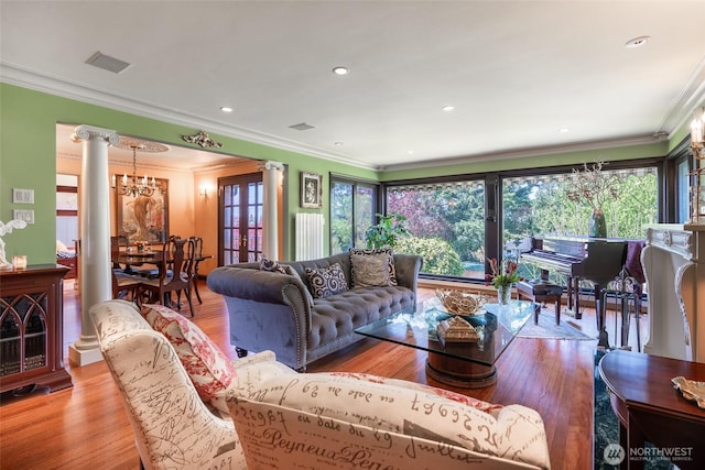 living room featuring plenty of natural light, ornate columns, wood finished floors, and a chandelier
