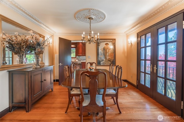 dining area featuring baseboards, french doors, light wood-type flooring, and a chandelier